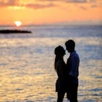 A couple sharing a romantic moment on a beach at sunset, creating a beautiful silhouette.
